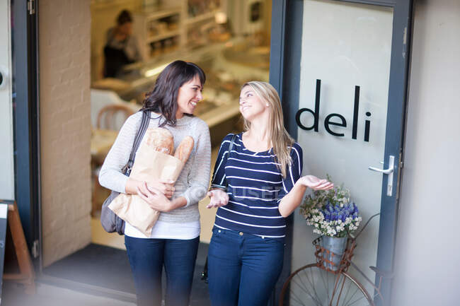 Women leaving delicatessen with bread — Stock Photo