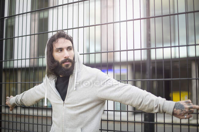 Homem adulto médio em pé contra cerca, olhando para longe — Fotografia de Stock