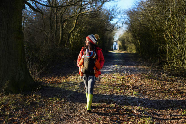 Donna che cammina lungo il sentiero di campagna, portando il bambino in fionda — Foto stock