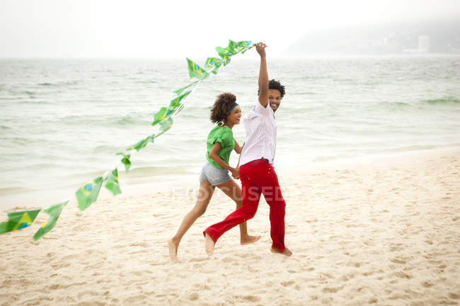 Пара, играющая со струной флагов на пляже, Рио-де-Жанейро, Бразилия — стоковое фото