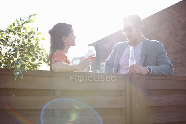 Mid adult couple chatting at fence at rooftop party — Stock Photo