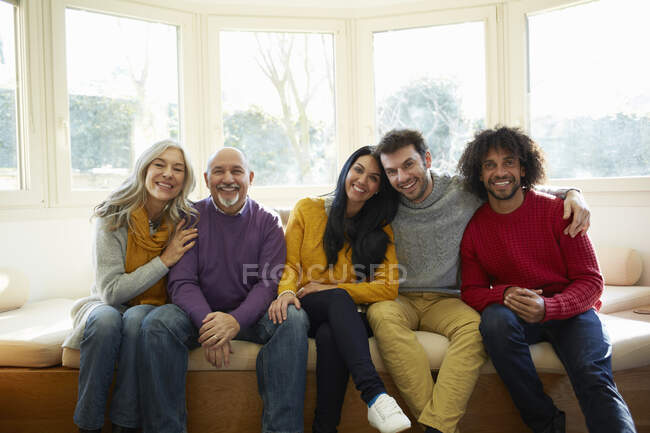 Familia lado a lado en el asiento de la ventana mirando a la cámara sonriendo - foto de stock