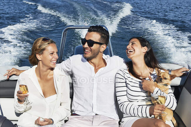Hombre joven en barco con los brazos alrededor de las mujeres, Gavle, Suecia - foto de stock