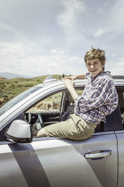 Porträt eines halbwüchsigen Jungen, der auf dem Fenster eines Geländewagens sitzt, Bridger, Montana, USA — Stockfoto
