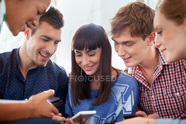 Group of five friends using smartphones — Stock Photo