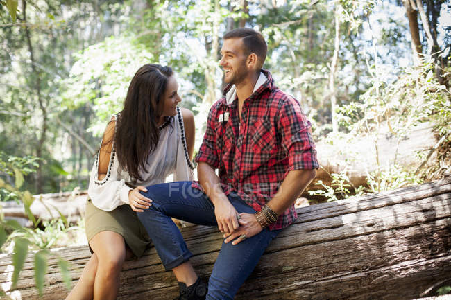 Giovane coppia seduta su un albero nella foresta — Foto stock