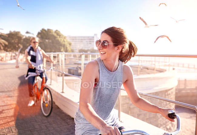 Mujer montar en bicicleta en el paseo marítimo - foto de stock