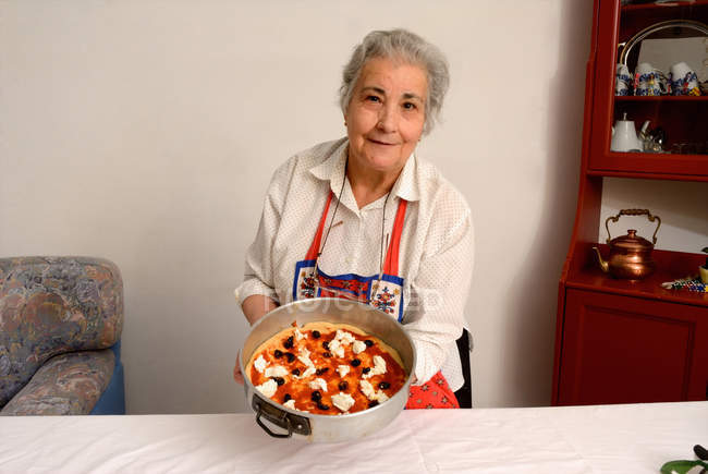 Femme plus âgée faisant des pizzas dans le salon — Photo de stock