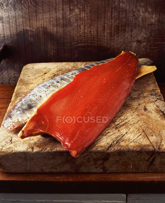 Filete ahumado de salmón sobre tabla de cortar de madera - foto de stock