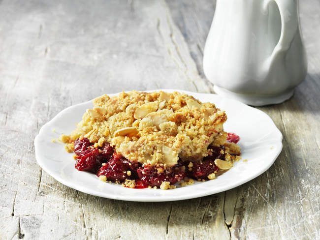 Sour cherry and almond crumble pudding on white plate — Stock Photo