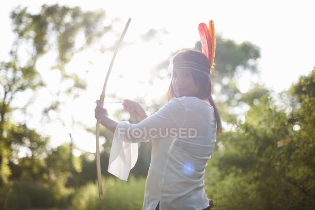 Retrato de mulher madura em bosques visando arco e flecha — Fotografia de Stock