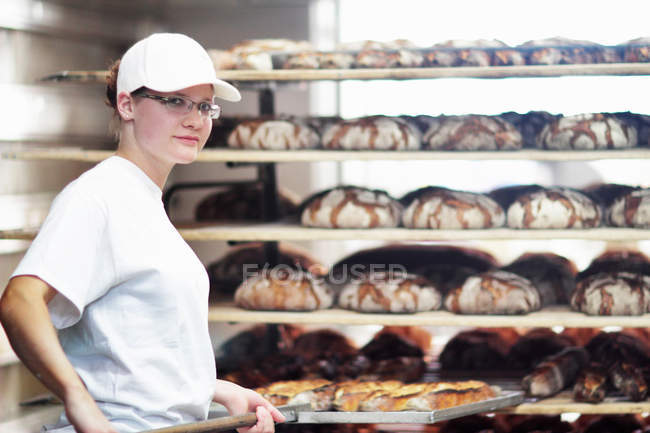 Baker poniendo pan en el estante - foto de stock