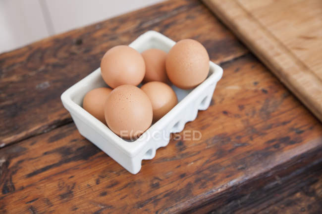 Carton of eggs on wooden kitchen counter — Stock Photo