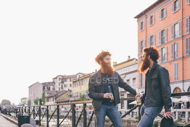 Junge männliche Hipster-Zwillinge mit roten Haaren und Bärten unterhalten sich am Ufer des Kanals — Stockfoto