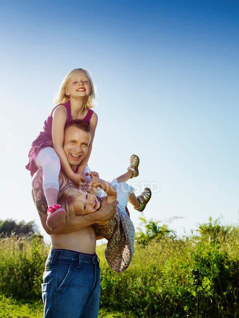 Отец играет с дочерьми на открытом воздухе — стоковое фото