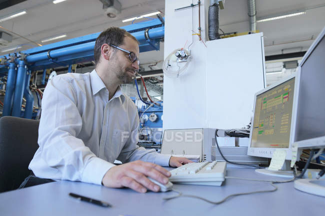 Manager monitoring information on computer in industrial plant — Stock Photo