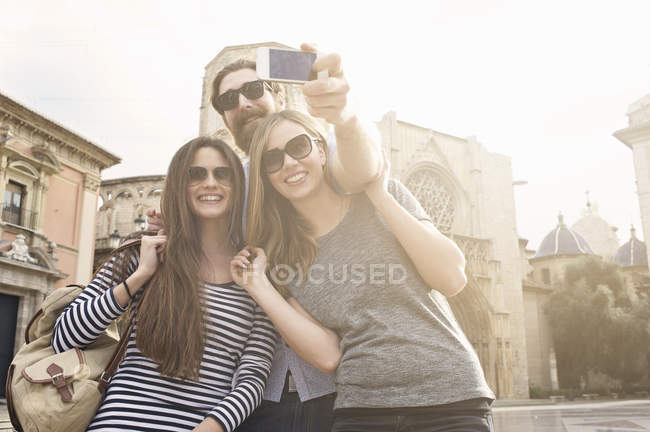 Tres turistas tomando autorretrato, Plaza de la Virgen, Valencia, España - foto de stock