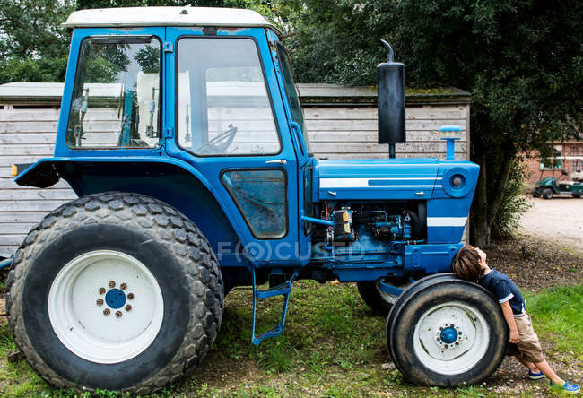 Junge lehnt an Traktor — Stockfoto