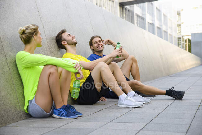 Троє друзів сидять на підлозі в спортивному одязі — стокове фото