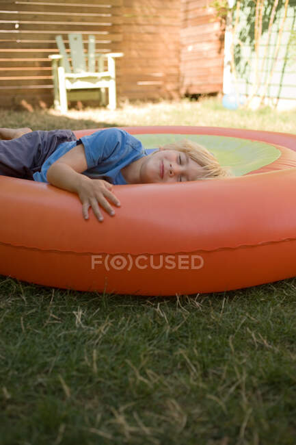 Молодий хлопчик лежить на надувному — стокове фото