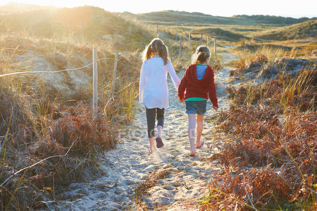 Two girls walking on sand dunes — Stock Photo