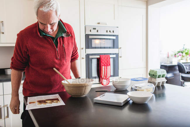 Старший чоловік вивчає рецепт на кухонній лічильнику — стокове фото