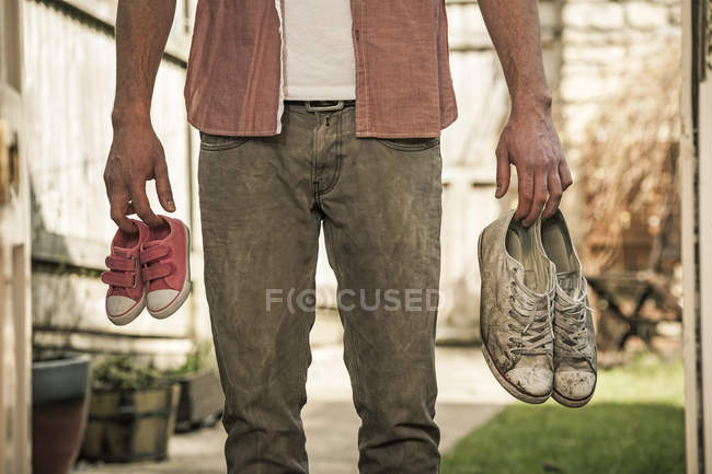 Hombre sosteniendo zapatos fuera de una puerta abierta - foto de stock