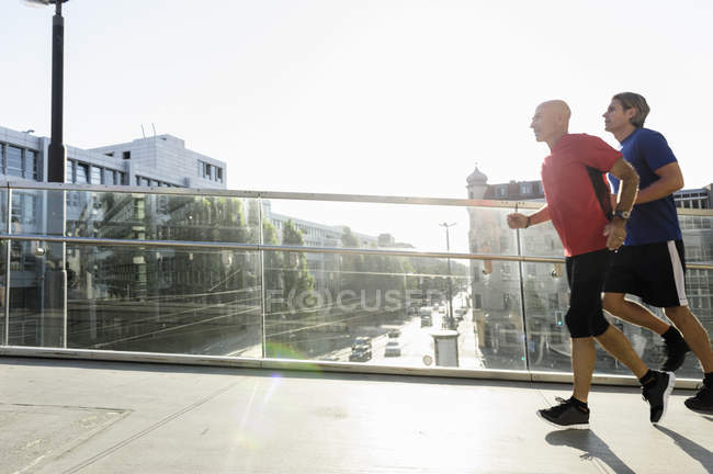 Dois corredores do sexo masculino atravessando ponte, Munique, Alemanha — Fotografia de Stock