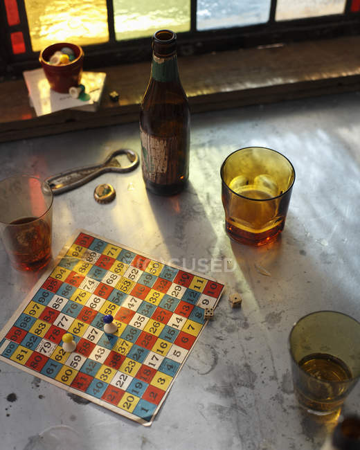 High angle view of beer bottle and board game on rustic table — Stock Photo