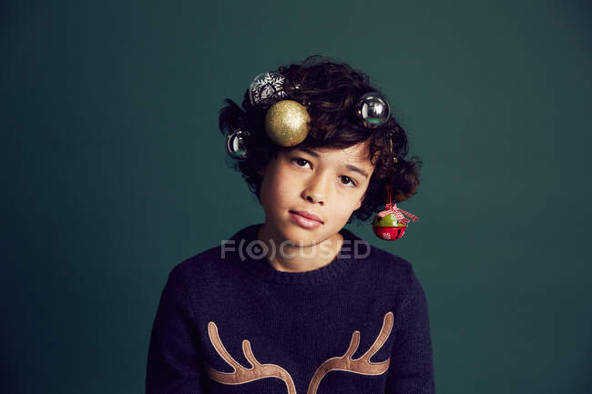 Portrait d'un adolescent portant un pull de Noël et des boules dans les cheveux — Photo de stock