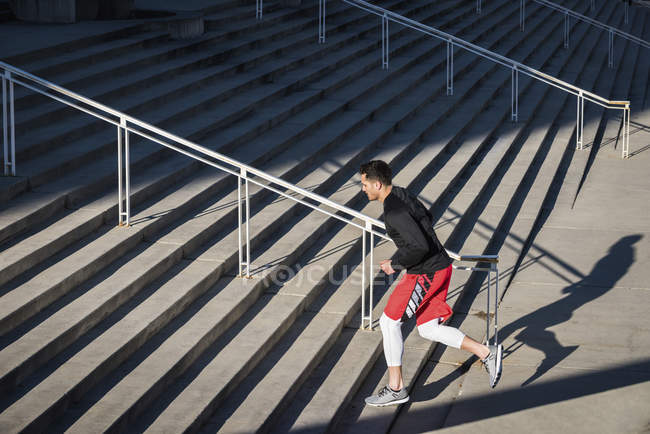 Молодой человек тренируется, бежит вверх по городской лестнице — стоковое фото