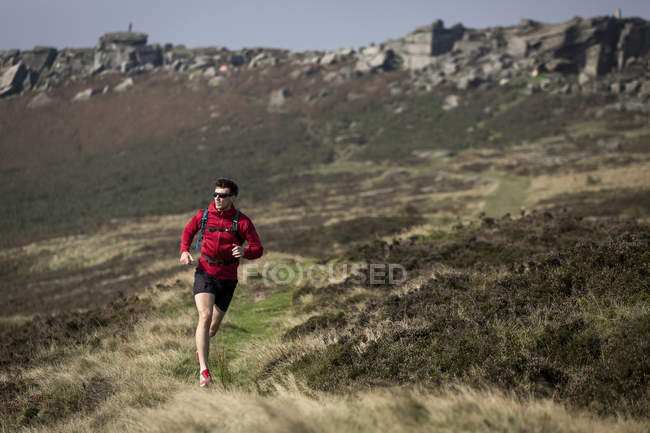 Corredor masculino corriendo cerca de Stanage Edge, Peak District, Derbyshire, Reino Unido - foto de stock
