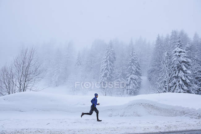 Distant view of male runner running in deep snow, Gstaad, Switzerland — Stock Photo