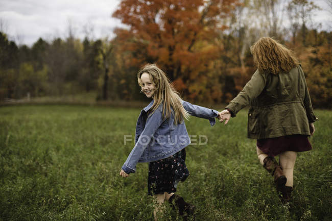 Madre e figlia che si tengono per mano camminando nel prato, Lakefield, Ontario, Canada — Foto stock
