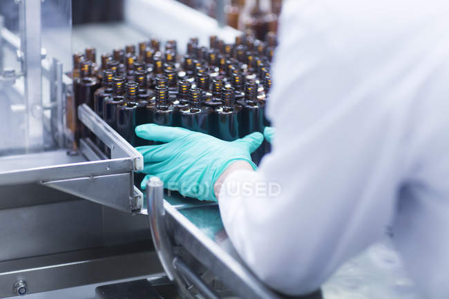 Cropped image of male worker hand in glove holding bottles — Stock Photo