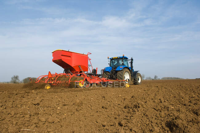 Trator puxando equipamentos para plantar sementes no campo — Fotografia de Stock