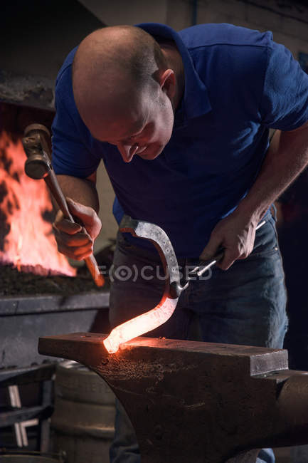 Farrier forching horseshoe on anvil — стоковое фото