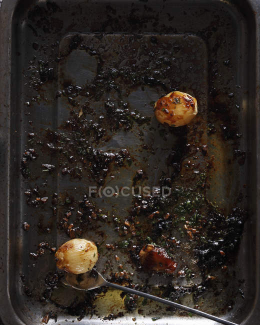 Baking tin with leftover roasted onions — Stock Photo