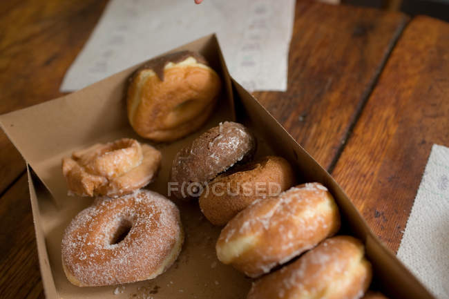 Caixa aberta de donuts na mesa de madeira — Fotografia de Stock