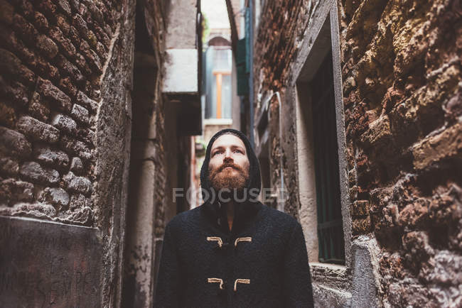 Uomo di mezzo adulto in cappotto incappucciato fisso da vicolo, Venezia, Italia — Foto stock