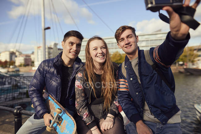 Три друзям, сидячи на вулиці, беручи selfie з камерою, Брістоль, Великобританія — стокове фото