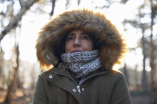 Retrato de mulher madura usando capuz de pele e cachecol na floresta — Fotografia de Stock
