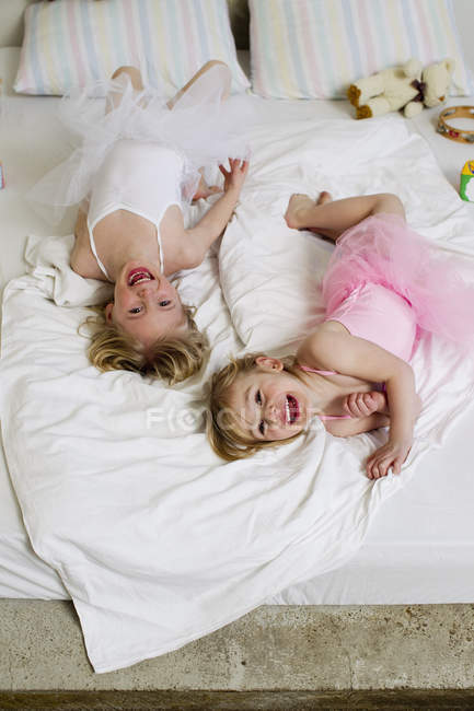 Портрет двух сестёр, играющих на кровати — стоковое фото