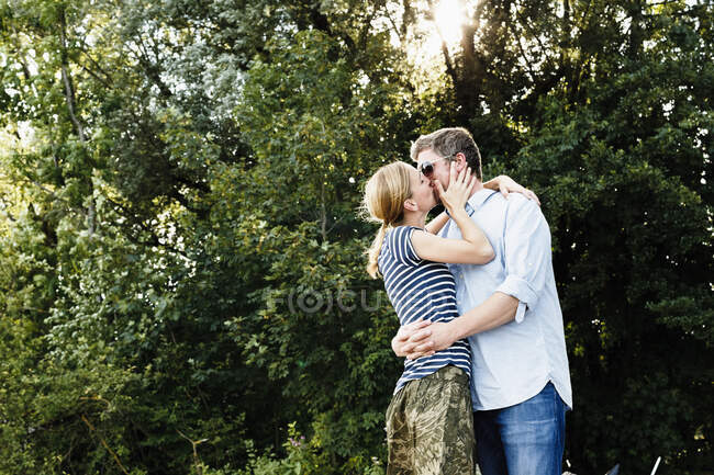 Pareja compartiendo apasionado beso en parque - foto de stock