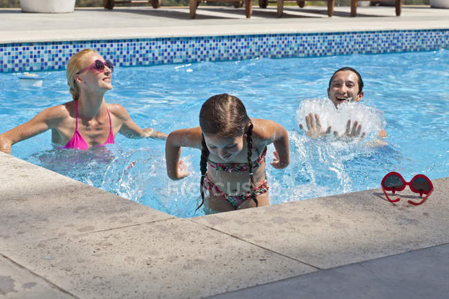 Jeune famille s'amuser dans la piscine extérieure — Photo de stock