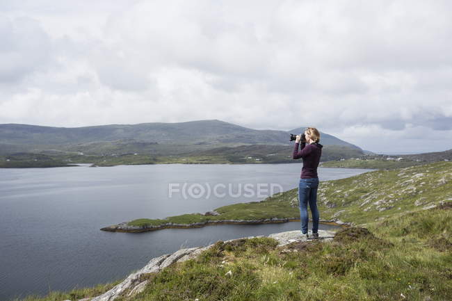 Woman photographing view, standing on north shore of East Loch Tarbet, North Harris, Outer Hebrides, Scotland — Stock Photo