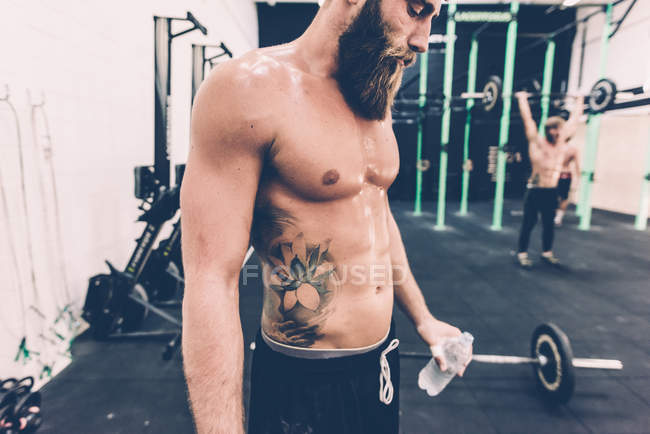 Homme cross-trainer prendre une pause de l'eau de l'haltérophilie dans la salle de gym — Photo de stock