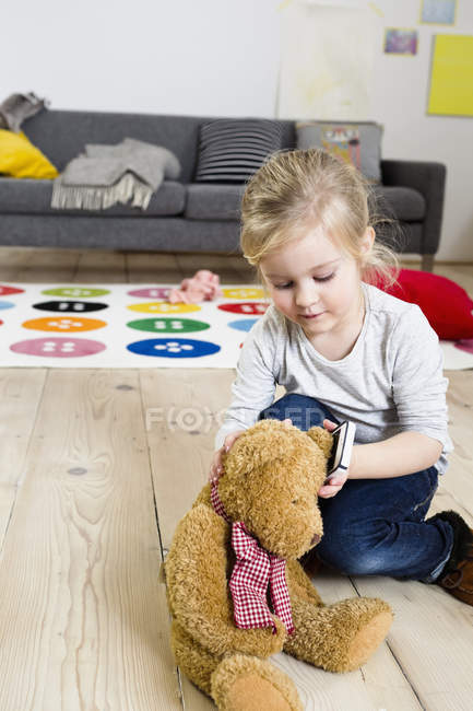 Дівчина грає з плюшевим ведмедем вдома — стокове фото
