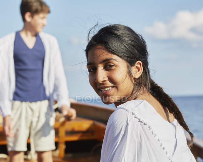 Femme sur le bateau regardant par-dessus l'épaule à la caméra souriant dans l'océan bleu — Photo de stock