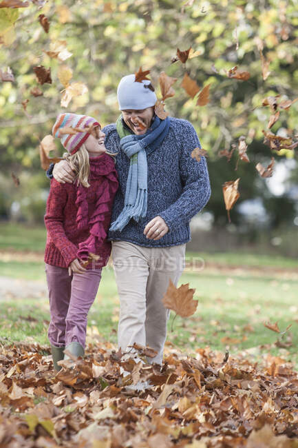 Отец и дочь валяют дурака в парке, ходят по осенним листьям — стоковое фото